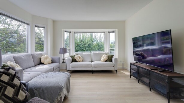 A modern living room with a grey sofa, a white sofa, and a TV on a stand. - Okanagan Escape (Kelowna)