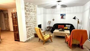 A living room with a stone wall, a wooden chair, a black sofa, and a coffee table.