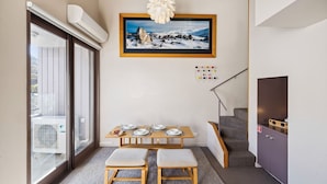 A compact living space with a dining area, a staircase, and a view through a glass door.