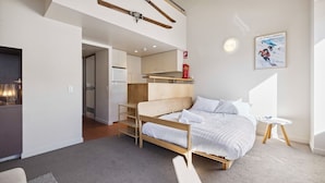 A modern bedroom with a bed, a small table, and a kitchenette.