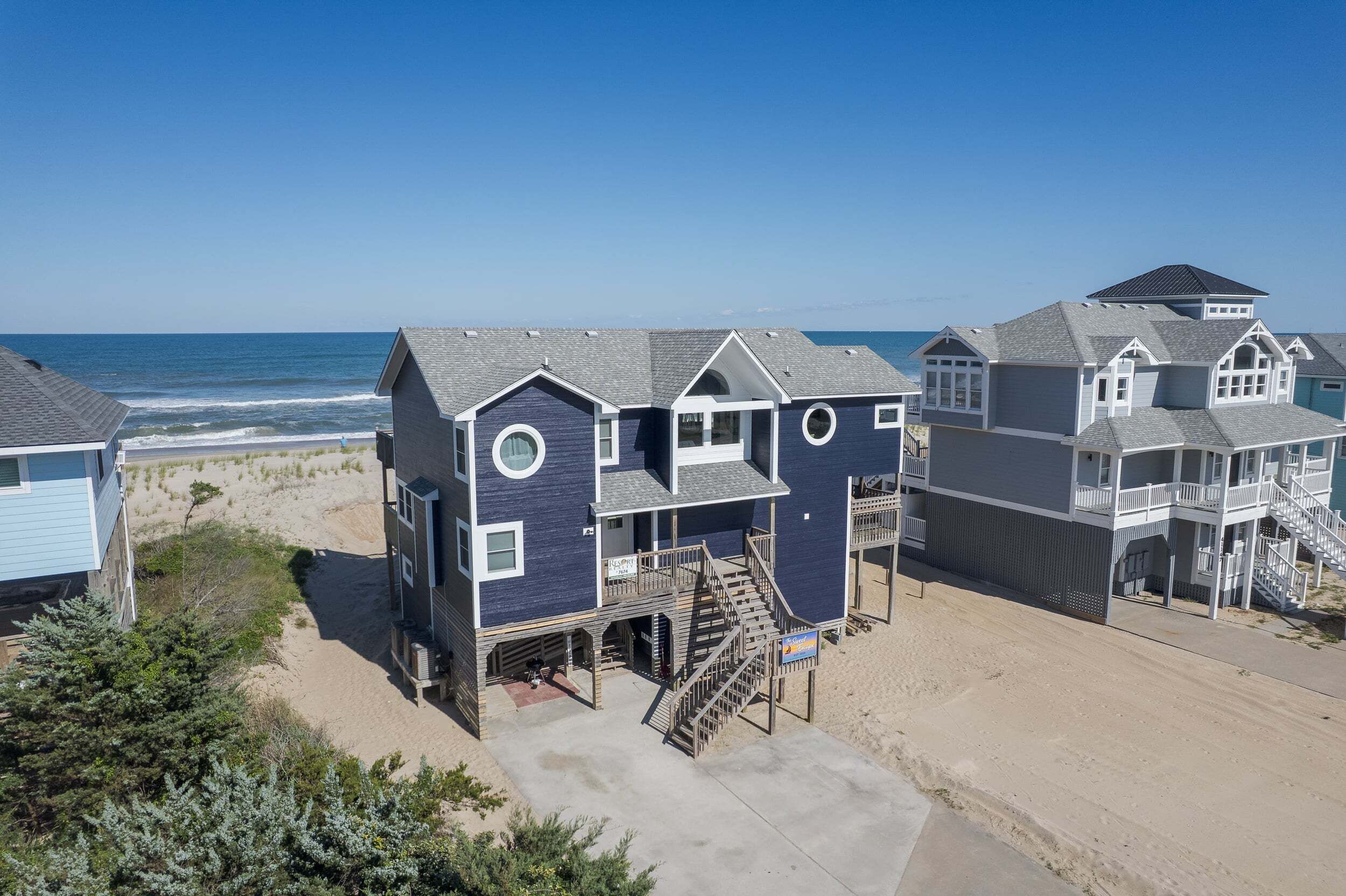 Une propriété située en bord de mer, comprenant plusieurs maisons, une plage de sable et l’océan en toile de fond.
