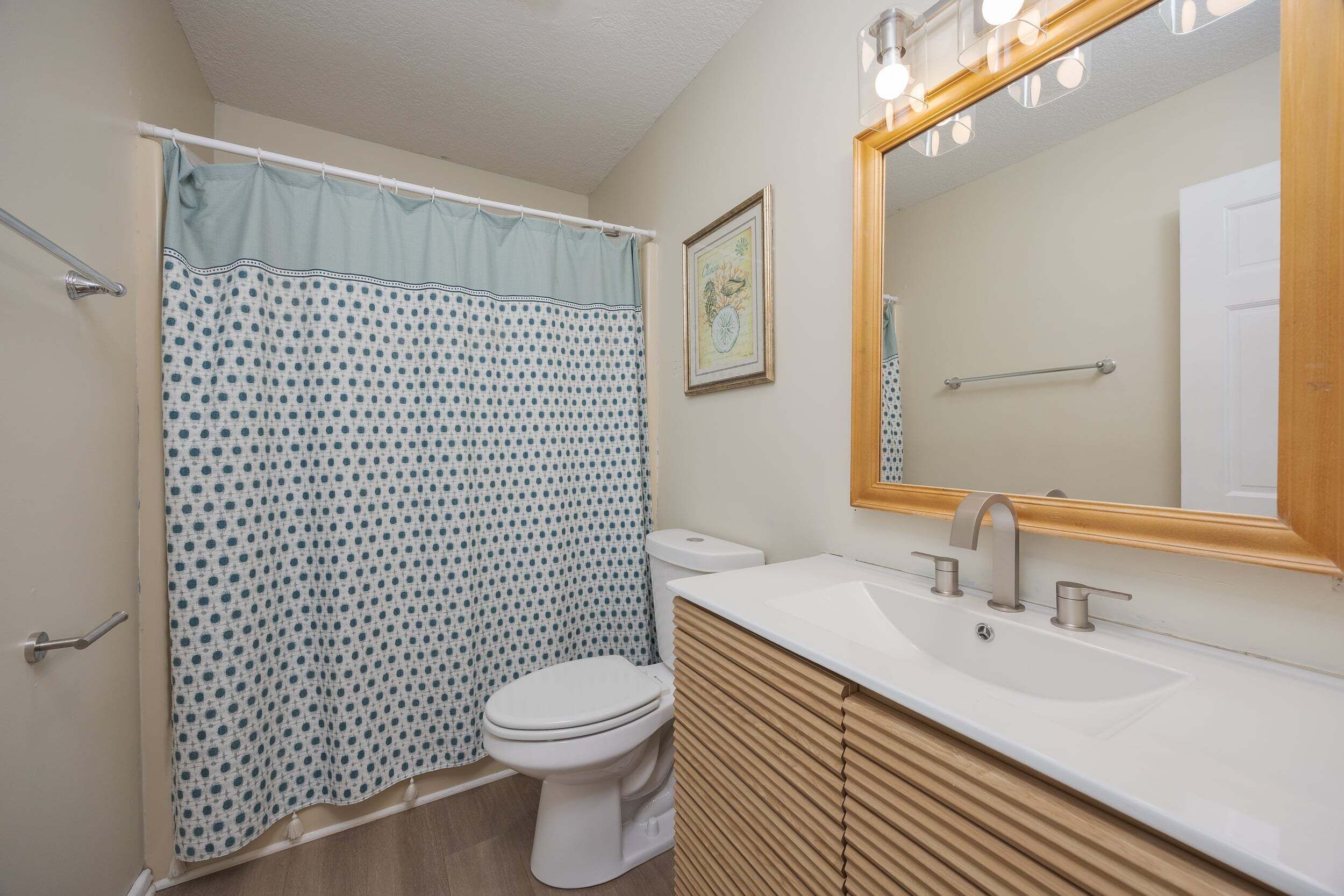 A bathroom with a toilet, sink, mirror, and shower curtain.