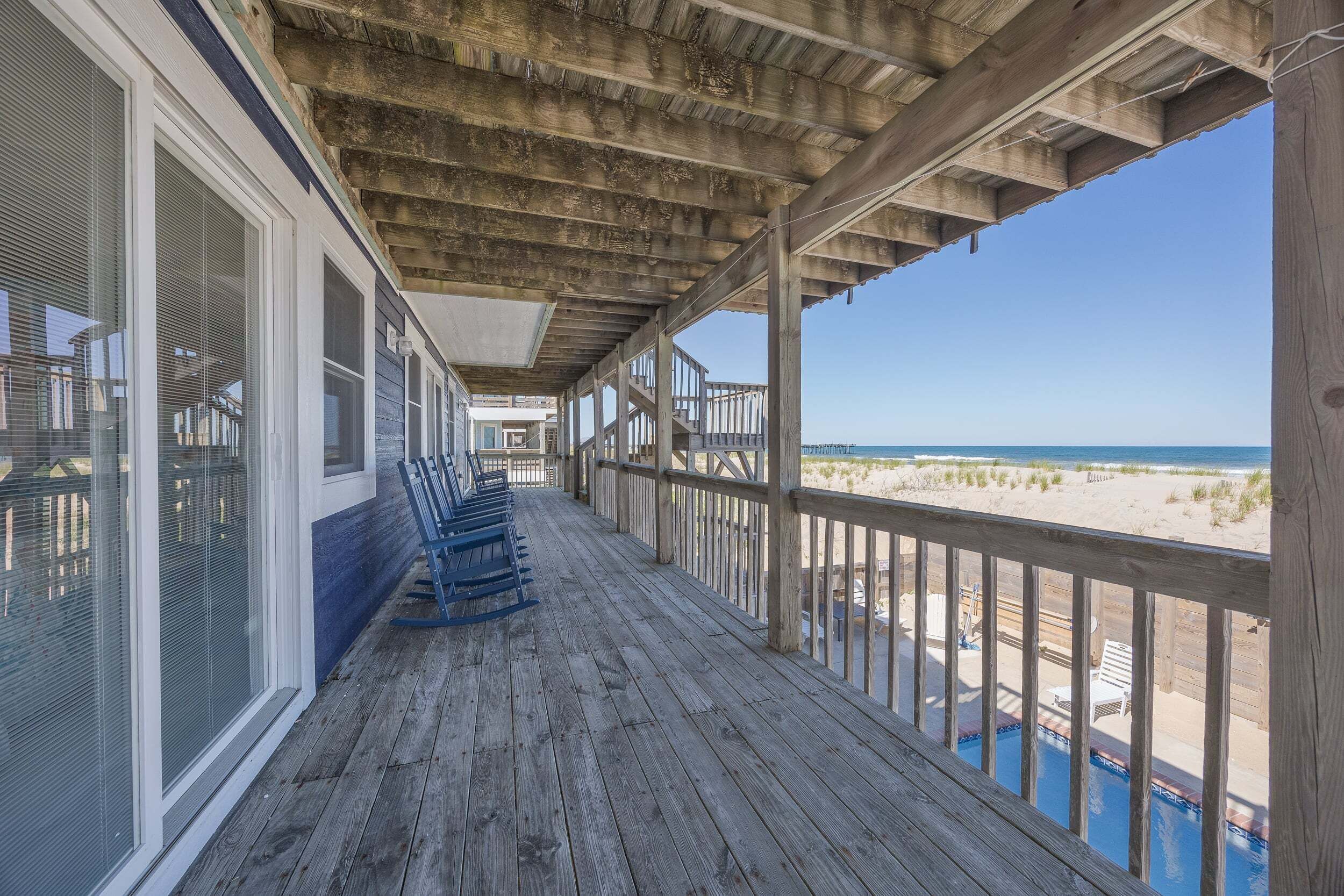Una terraza de madera con vista a la playa y al océano.
