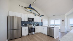 Una cocina moderna con armarios blancos, electrodomésticos de acero inoxidable, una salpicadura y un gran mural de peces en el techo.