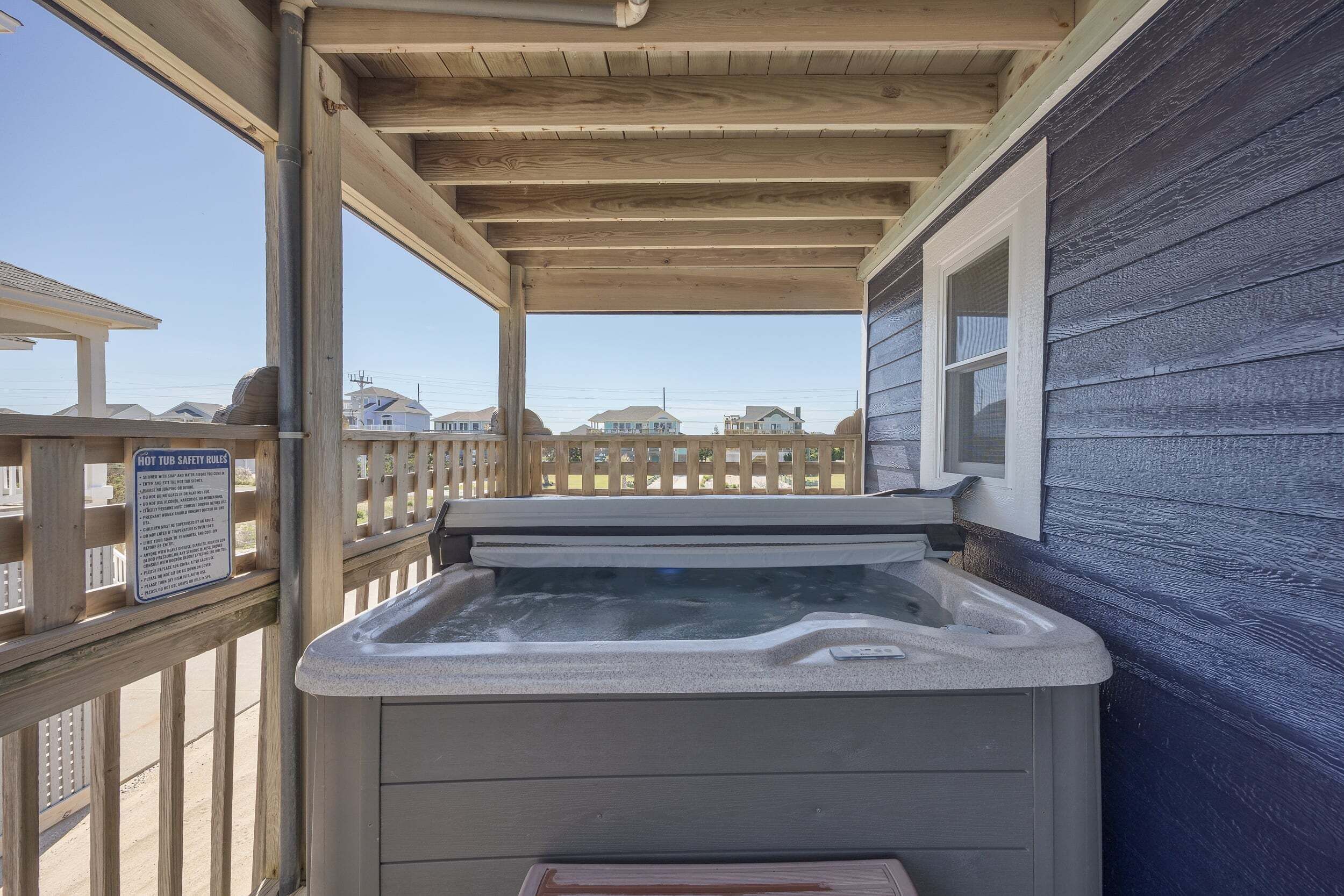 A hot tub with a wooden deck and a safety sign.