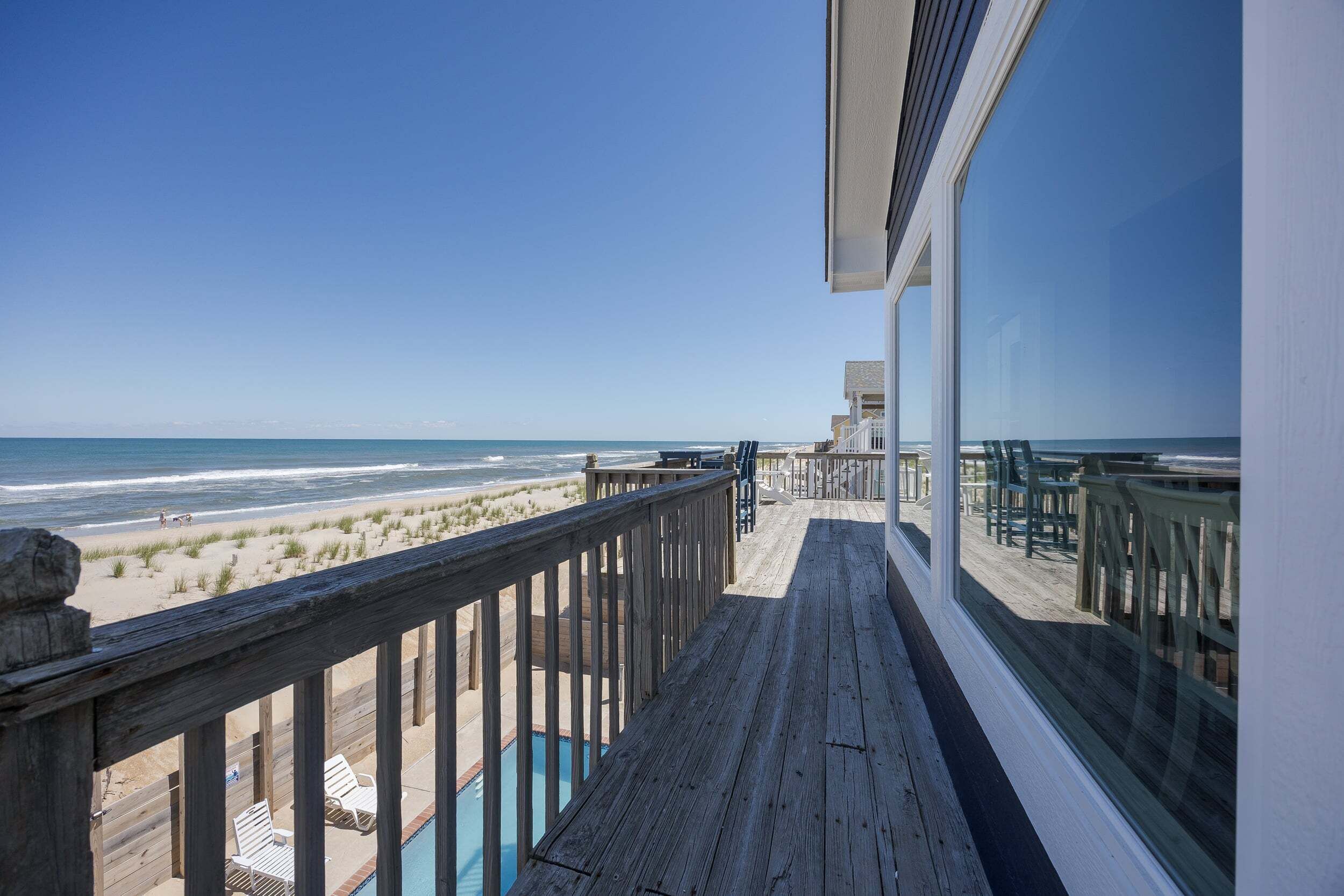 Une terrasse en bois offrant une vue sur la plage et l’océan.