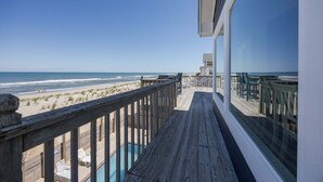 Una terraza de madera con vista a la playa y al océano.