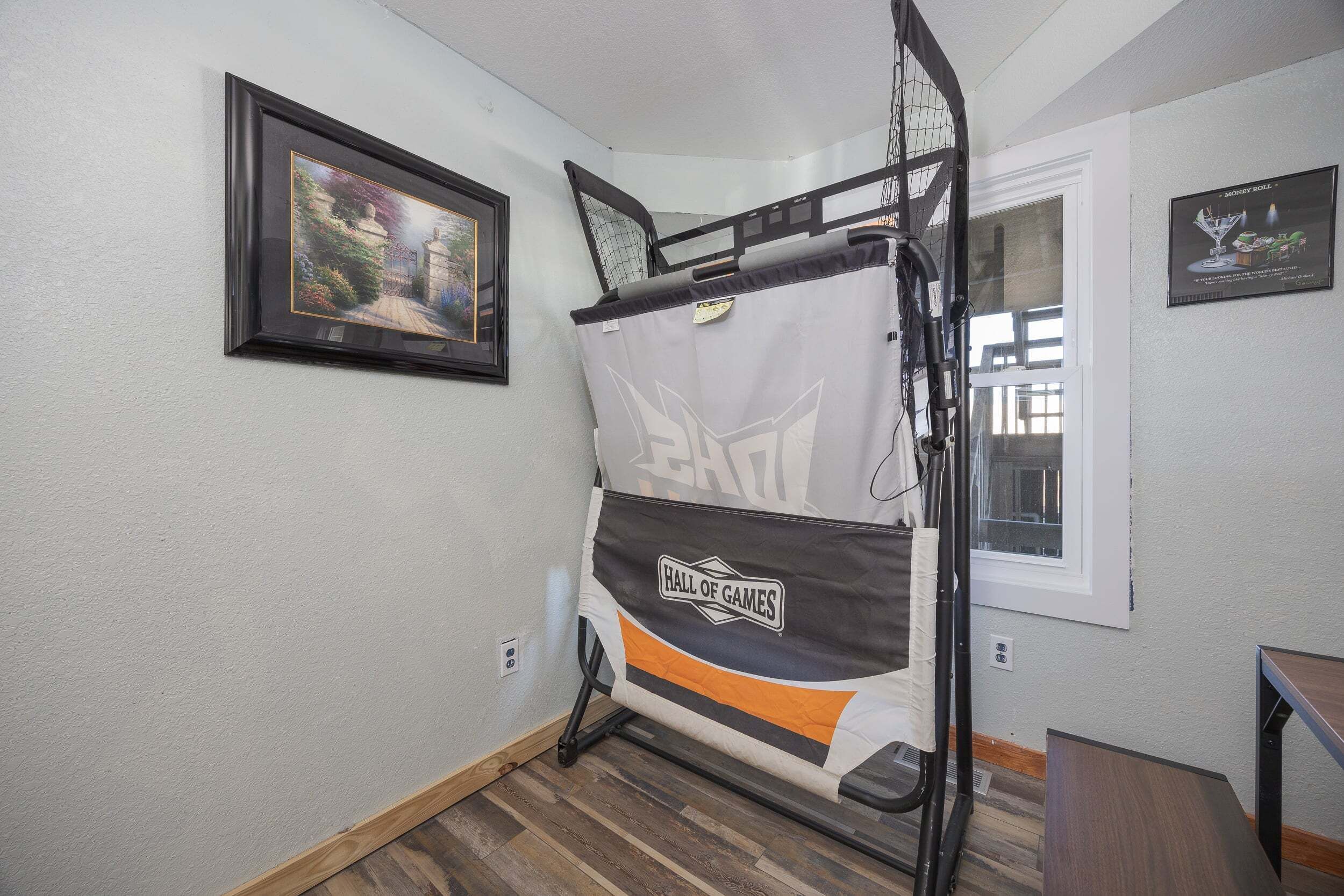 Un lit superposé orné d’une banderole « Salle de jeux », une photo encadrée accrochée au mur et une fenêtre avec des stores.