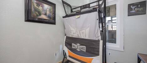 Un lit superposé orné d’une banderole « Salle de jeux », une photo encadrée accrochée au mur et une fenêtre avec des stores.