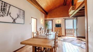 Ein Holzespeisesaal mit Stühlen, ein Fernseher auf einer Holzkommode und ein Hirschgemälde an der Wand.