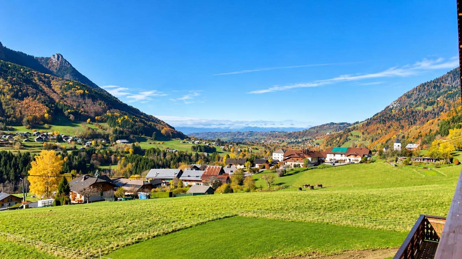 Un paysage rural avec des maisons, des champs et des montagnes.
