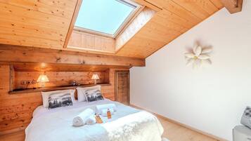 Une pièce chaleureuse aux murs en bois, dotée d’une lucarne, d’un lit avec des oreillers, d’une table de chevet et d’un élément décoratif mural.