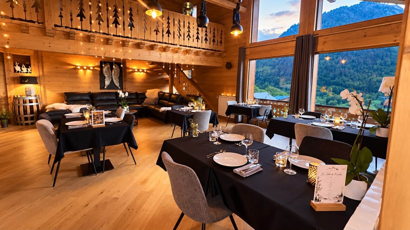 A dining area with tables set for a meal, wooden walls, and a view of the outdoors.