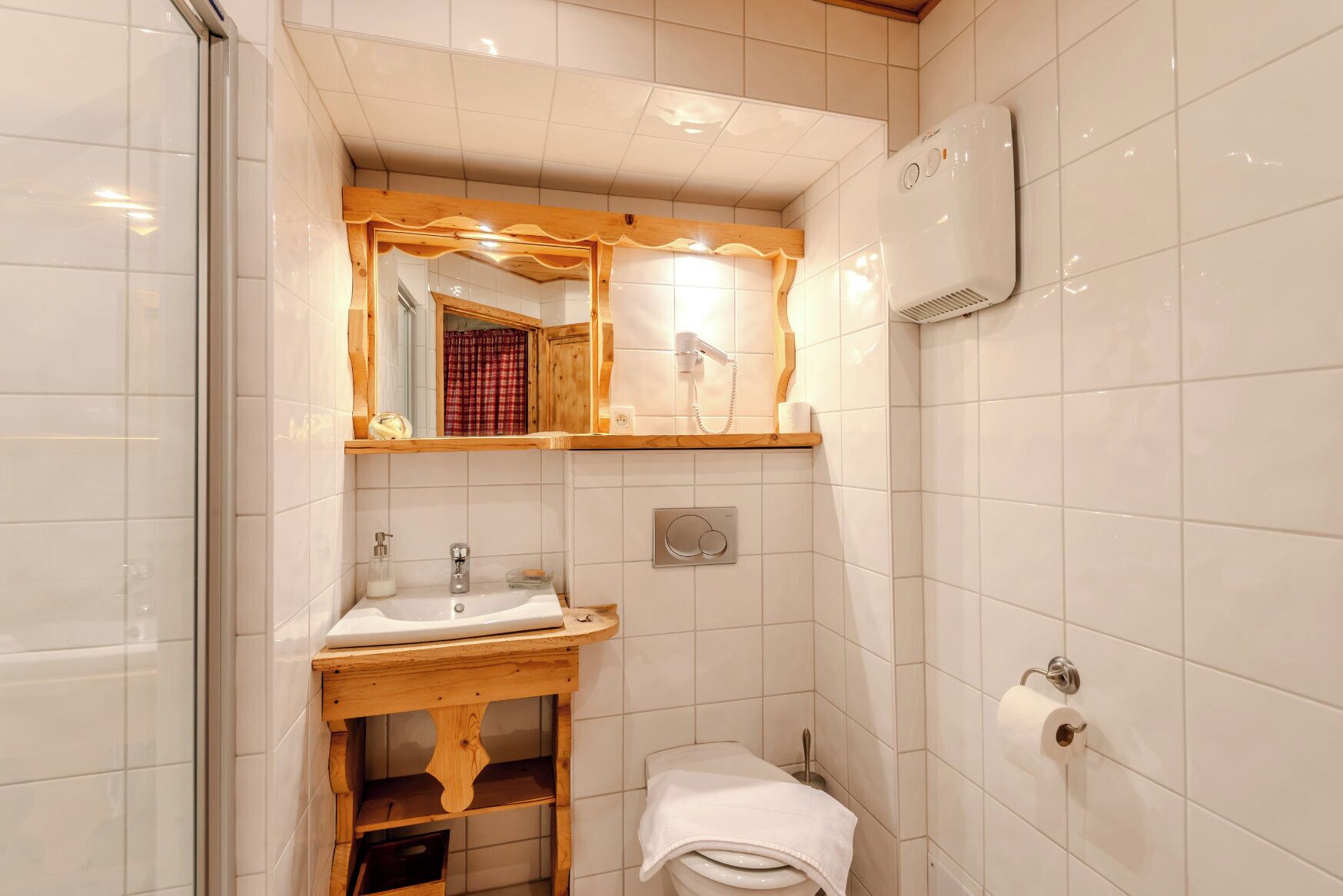 Une salle de bain avec un meuble-lavabo en bois, un évier, un miroir, un porte-serviettes et des toilettes.