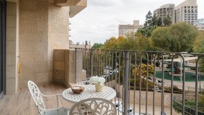Ein Balkon mit rundem Tisch, Stühlen und einer kleinen Pflanze.