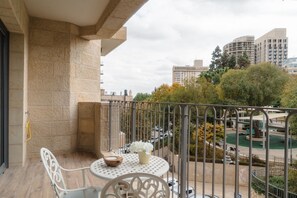Ein Balkon mit rundem Tisch, Stühlen und einer kleinen Pflanze.