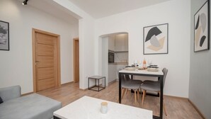 Un salon moderne avec un canapé gris, une table basse blanche et une porte en bois.