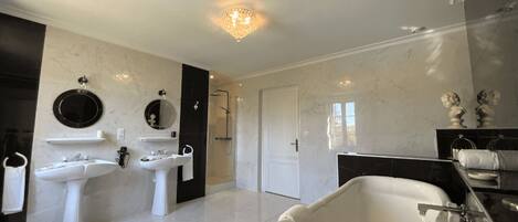 A modern bathroom with two sinks, a bathtub, and a shower.