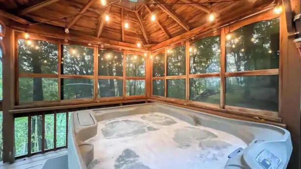 A hot tub in a wooden cabin with large windows and string lights. - Mountain View’s with hot-tub (Jasper)