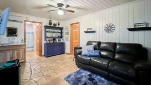 A living room with a black leather sofa, a blue rug, and a ceiling fan. - Mountain View’s with hot-tub (Jasper)