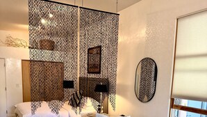 A modern living room with a white sofa, patterned throw, and a round wooden coffee table with books and a remote control. - Spacious Design Loft/Railyard Distr; soaking tub (Santa Fe)