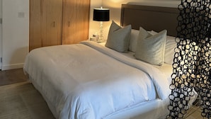 A bedroom with a large bed, a wooden wardrobe, a framed picture on the wall, and a unique black decorative piece. - Spacious Design Loft/Railyard Distr; soaking tub (Santa Fe)