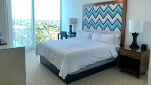 Ein Hotelzimmer mit einem großen Bett, einem Deckenventilator, Blick auf die Stadt und einer Wanddekoration.
