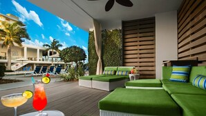 Eine moderne Lounge-Bereich im Freien mit grünen Sitzmöglichkeiten, einem Pool und Blick auf ein Hotelgebäude.