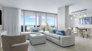 Ein modernes Wohnzimmer mit einer großen Couch, einem Esstisch und Blick auf den Ozean.
