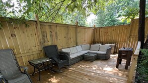 A wooden deck with a sectional sofa, two chairs, and a small table.