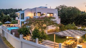 A modern two-story house with a swimming pool, outdoor seating, and a covered patio area.