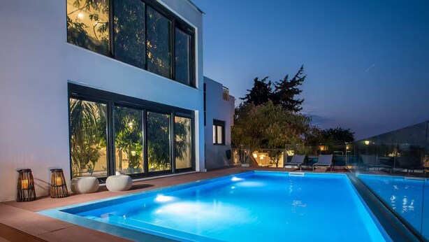 A modern poolside area with a clear blue pool, large windows, and outdoor seating.
