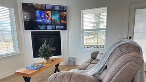 Una sala de estar con un sofá de cuero marrón, una mesa de centro de madera, un televisor de pantalla plana montado en la pared y una pequeña planta en maceta.