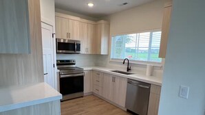 Una cocina moderna con armarios de madera clara, electrodomésticos de acero inoxidable y un ventanal que proporciona luz natural.