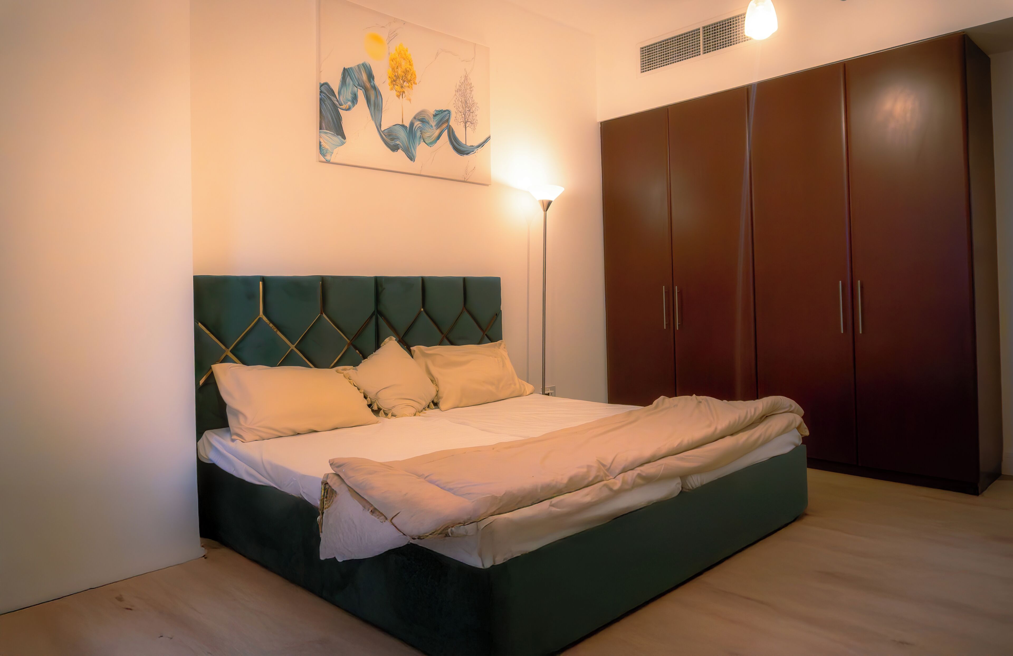 Ein Schlafzimmer mit Bett, Kopfteil, Kleiderschrank und einem Bild an der Wand.