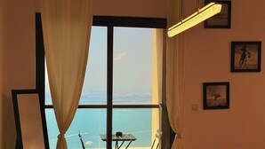 A room with a large window, a table with chairs, and a hanging light fixture.