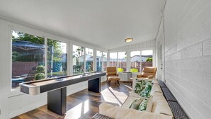 A spacious indoor area with a pool table, comfortable seating, and large windows offering views of the outdoors.