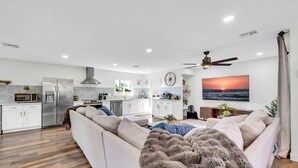 A modern kitchen with white cabinets, a stainless steel refrigerator, and a microwave.
