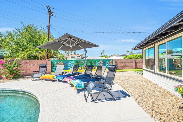 A backyard with a swimming pool, lounge chairs, and a mural wall. - Scottsdale Getaway, Resort Backyard and Game Room (Scottsdale)