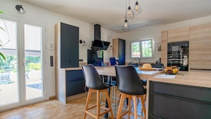 A modern kitchen with a central island, bar stools, a built-in oven, and a large window providing natural light. - Lovely home in Saint Cezaire (Saint Cezaire)