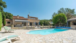 A pool area with stone flooring, lounge chairs, and a building with a tiled roof. - Lovely home in Saint Cezaire (Saint Cezaire)