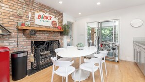 A modern kitchen with a brick wall, a white dining table, and chairs.