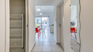 Un interior moderno con un pasillo que conduce a un comedor con sillas rojas y una mesa blanca.