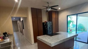 Una cocina moderna con encimera de granito, refrigerador integrado y ventilador de techo.