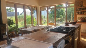 Cuina amb una illa gran, forn de foc i un rentaplat. Grans finestres ofereixen vista a l'exterior.