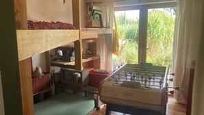 Habitació acollidora amb taula de futbolí, un ordinador i finestra amb vista a vegetació.