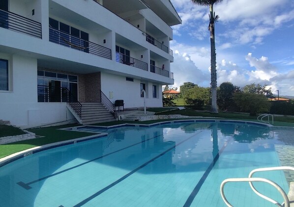 A swimming pool with a modern building in the background. - Finca El Encanto Calima (Calima)