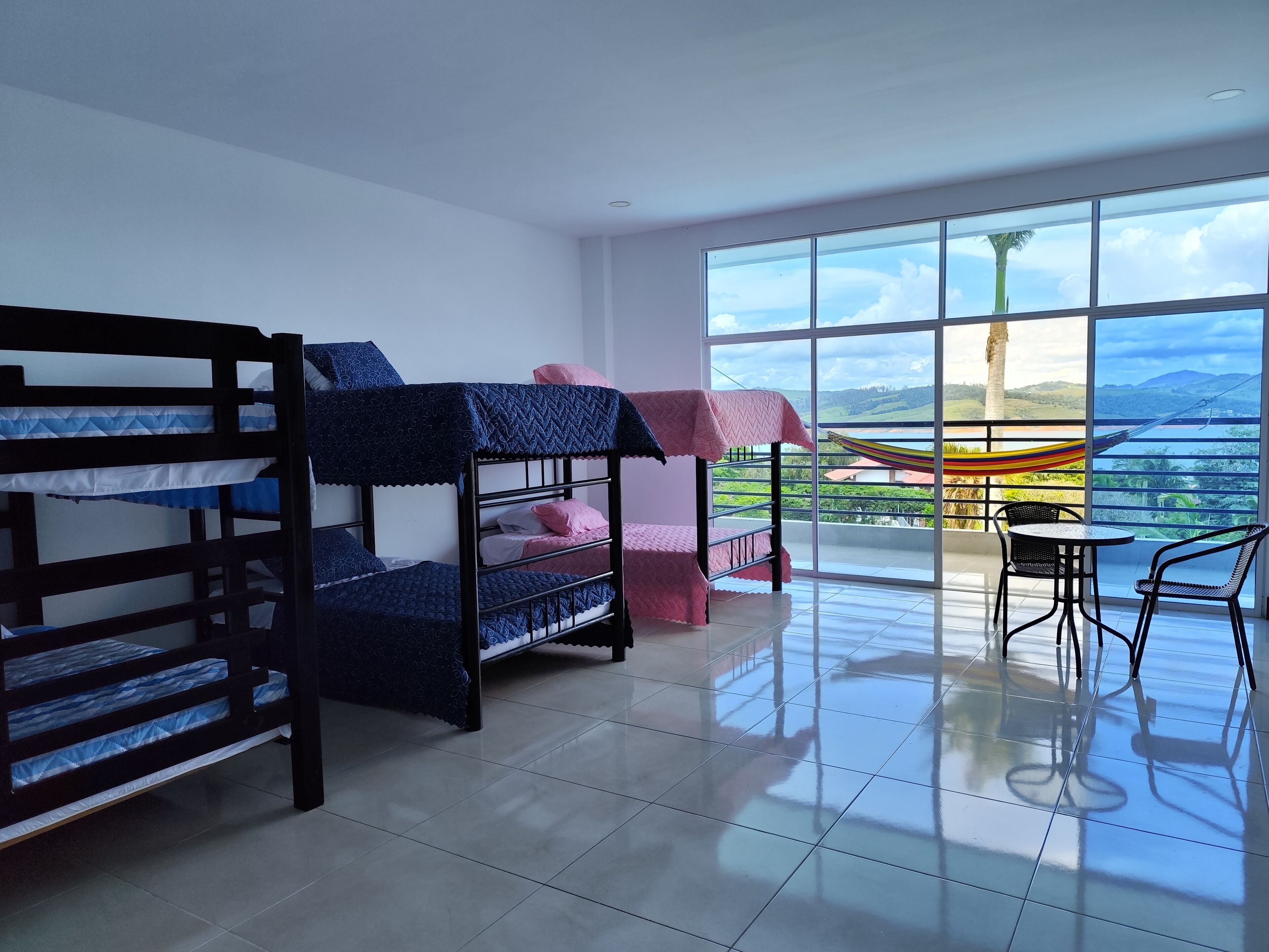 Una habitación con literas, un balcón con vistas y una mesa con sillas.
