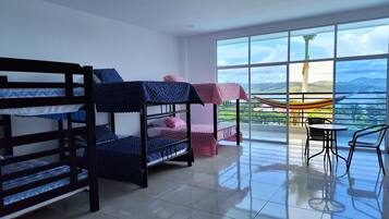 Una habitación con literas, un balcón con vistas y una mesa con sillas.