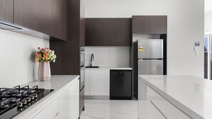 A modern kitchen with white countertops, dark wood cabinets, a stainless steel refrigerator, a dishwasher, and a gas stove. - Cork & Vine on Coolalta  - A Cellar Door Escape (Nulkaba)